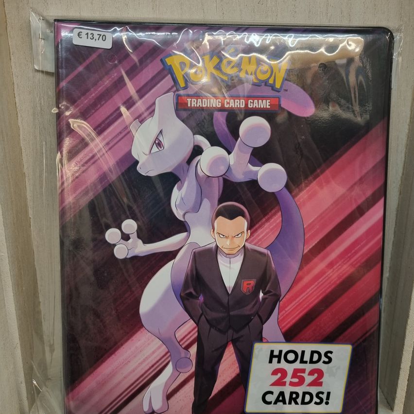Die Pokemon Trading Card Game-Abdeckung zeigt ein weißes Pokemon und einen Mann im Anzug. Der Kartenkoffer ist versiegelt und kostet 13,70 Euro. Er kann bis zu 252 Karten aufnehmen.