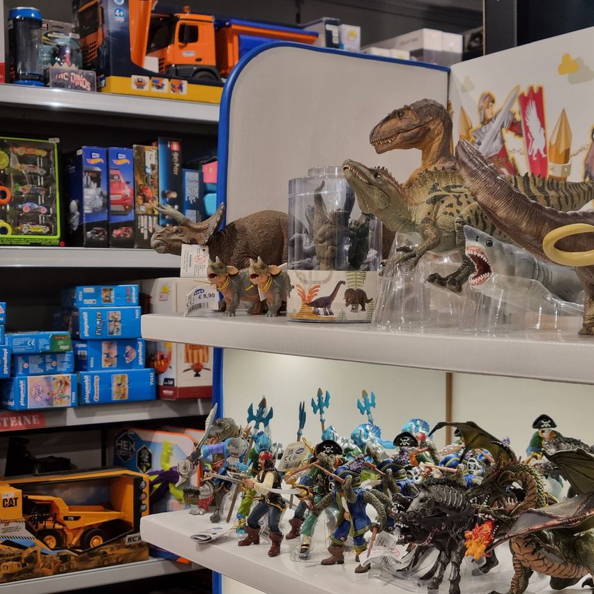 A toy store with various figurines and toys on display, including dinosaurs, pirates, and construction vehicles.