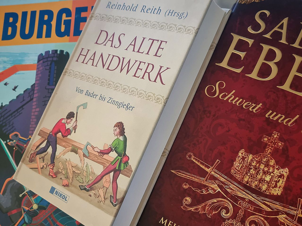 A book titled 'Das Alte Handwerk' is shown, featuring illustrations of historical craftsmen.