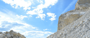 Ein Berg mit einem großen Haufen von Felsen unter einem klaren blauen Himmel mit einigen Wolken.