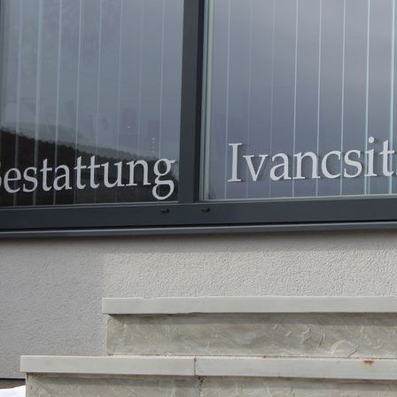 Ein Gebäude mit einem Glasfenster mit dem Wort Ivancysitun darauf. Das Fenster hat einen schwarzen Rahmen.