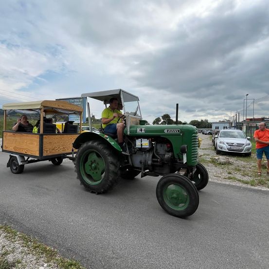 Bild enthält, Machine, Wheel, Car, Vehicle, Person, Shoe, Shorts, Tractor, Utility Pole, Outdoors