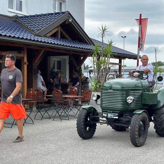 Bild enthält, Adult, Male, Man, Person, Wristwatch, Shorts, Shelter, Wheel, Vehicle, Tractor