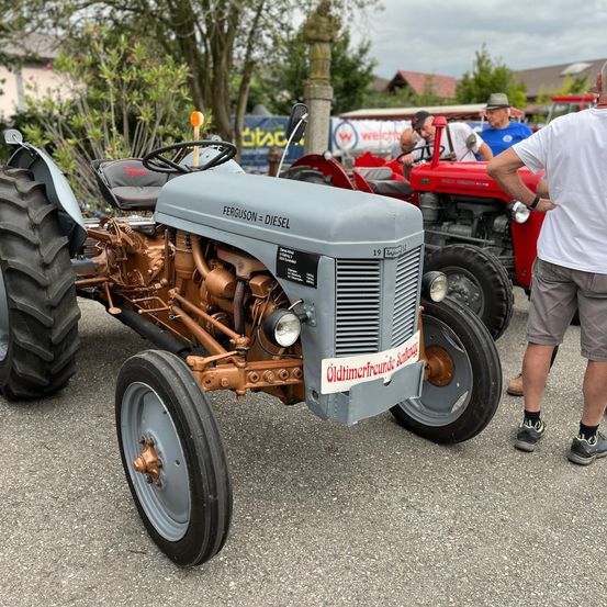 Bild enthält, Tractor, Vehicle, Adult, Male, Man, Person, Wheel, Tire, Shorts, Shoe