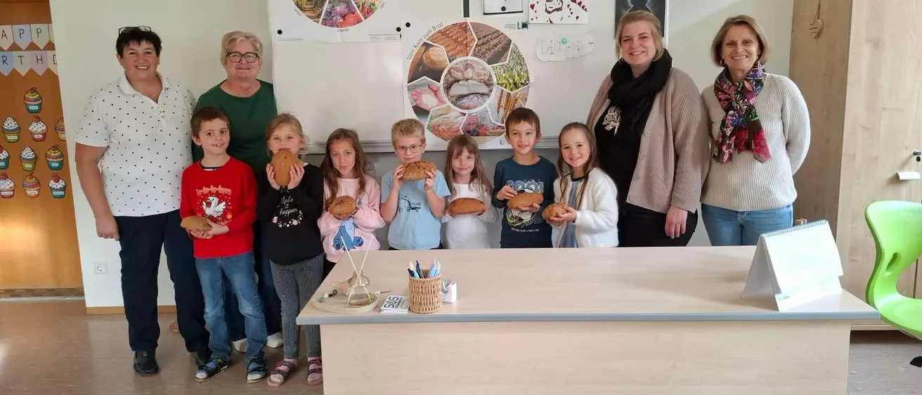 Eine Gruppe von Menschen steht in einem Raum, einige von ihnen halten Brot.