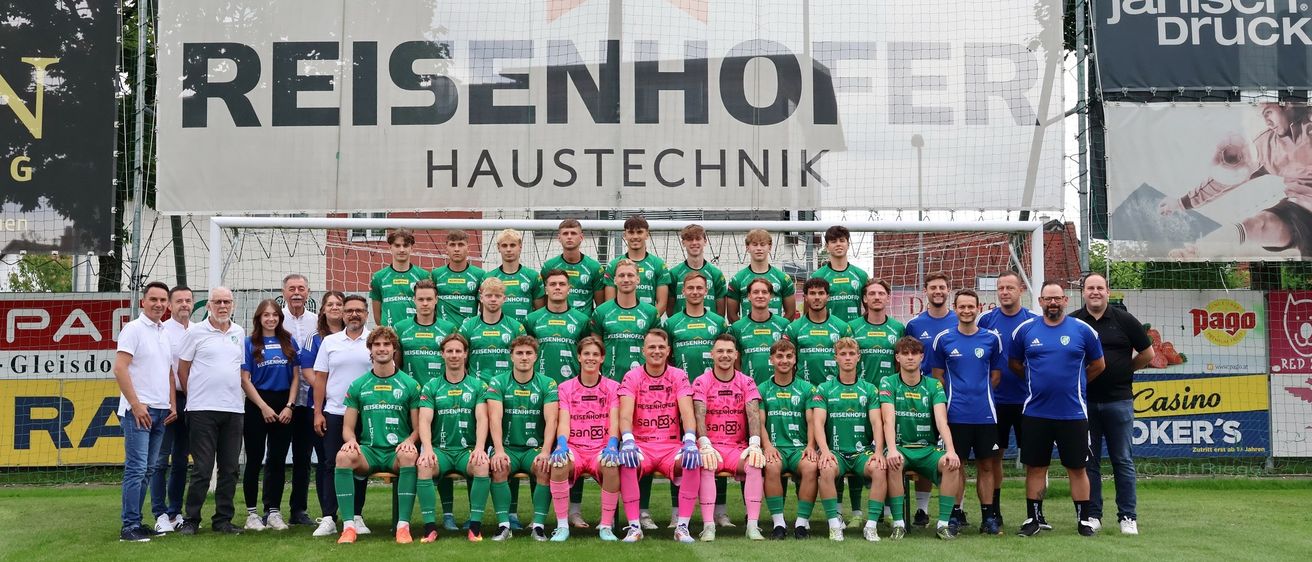 Eine Fußballmannschaft posiert für ein Foto vor einem Banner mit der Aufschrift Reisenhofer Haustechnik.