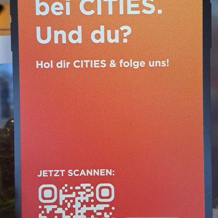 Ein rotes Schild mit weißem Text lautet 'bei CITIES. Und du? Hol dir CITIES & folge uns!' und einem QR-Code.