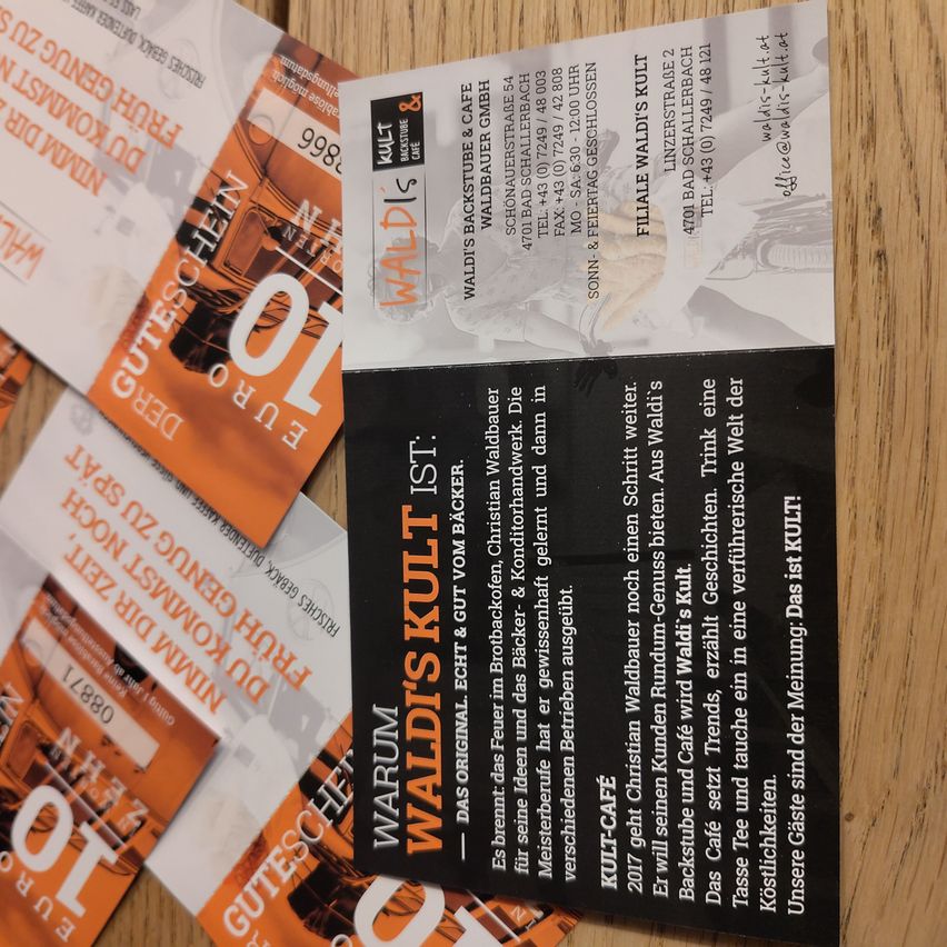Ein Flyer für Waldi's Kult wird gezeigt. Es hat ein schwarzes und oranges Farbschema mit Text darauf. Der Flyer hat einen unscharfen Effekt.