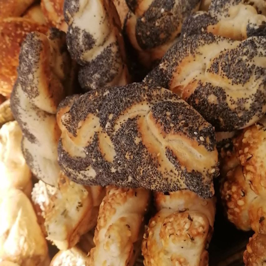 Ein Nahaufnahme verschiedener Backwaren, einschließlich Brezeln und Brötchen mit Sesam- und Mohnsamen, mit einer goldbraunen Kruste.