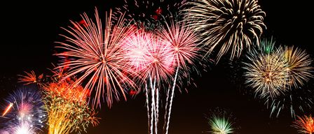 Eine farbenfrohe nächtliche Feuerwerksshow mit mehreren Explosionen am Himmel, die ein spektakuläres Farbenspiel erzeugen.