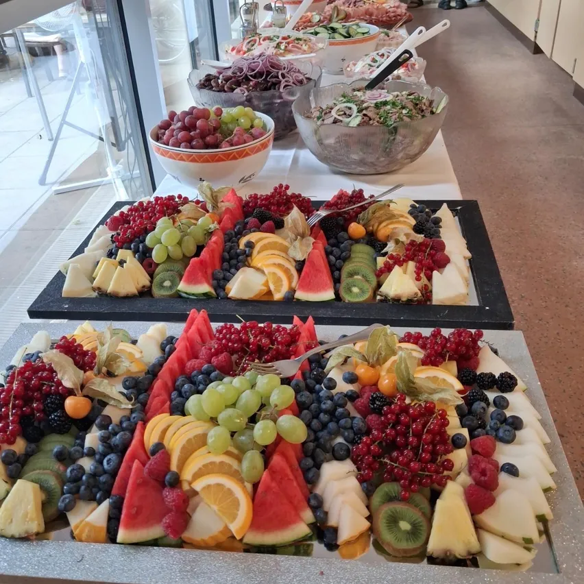 Ein Tisch voller verschiedener Obst- und Gemüsesorten, darunter Wassermelonen, Trauben, Kiwis und Orangen.