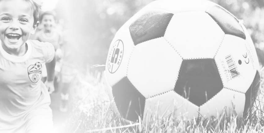 Ein Kind rennt auf einen Fußball auf einem Rasenfeld zu, trägt ein Trikot der Fußballmannschaft. Der Ball hat ein schwarz-weißes Muster.