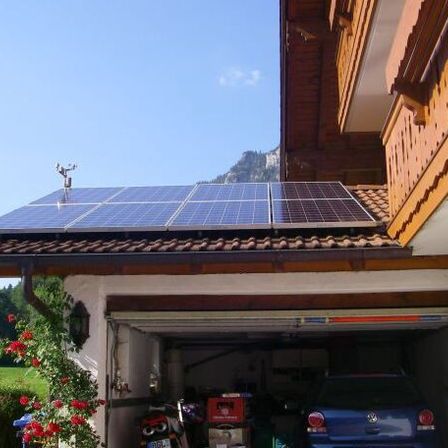 Ein Haus mit Solarpanelen auf dem Dach und einem Auto in der Garage.