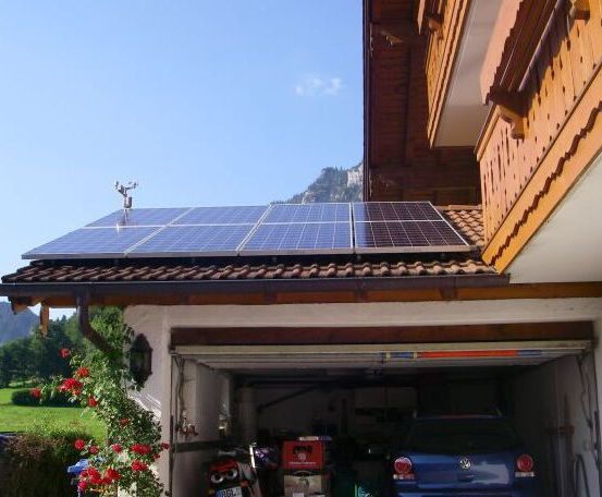 Ein Haus mit Solarpanelen auf dem Dach und einem Auto in der Garage.