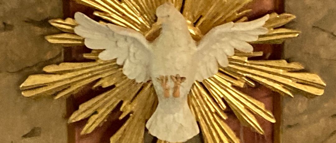 Eine goldene Taube, die den Heiligen Geist symbolisiert, ist auf einer Marmorkanzel mit goldenen Akzenten und roten und braunen Streifen montiert.
