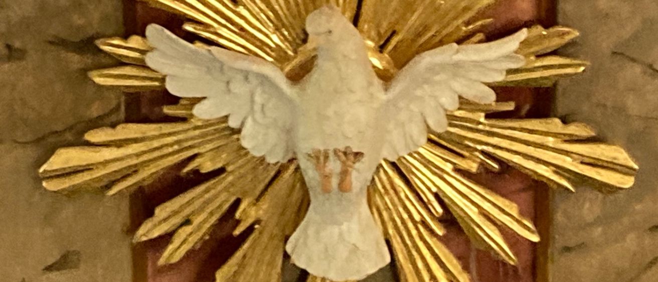 Eine goldene Taube, die den Heiligen Geist symbolisiert, ist auf einer Marmorkanzel mit goldenen Akzenten und roten und braunen Streifen montiert.