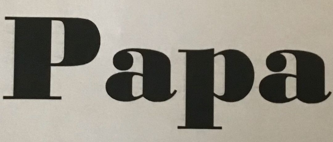 Ein Buch mit dem Titel 'Papa' von Elisabeth ist zu sehen. Der Einband hat ein großes Wort 'Papa' und ein herzförmiges Aufkleber mit einem lächelnden Gesicht.