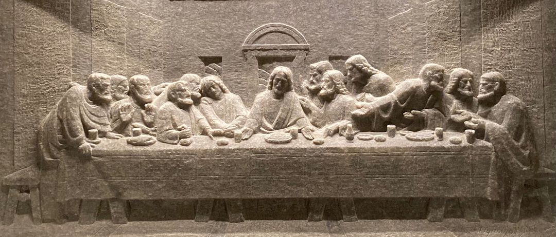 Ein Steinrelief der Szene des Letzten Abendmahls mit Jesus und seinen Jüngern um einen Tisch mit Brot und Wein.
