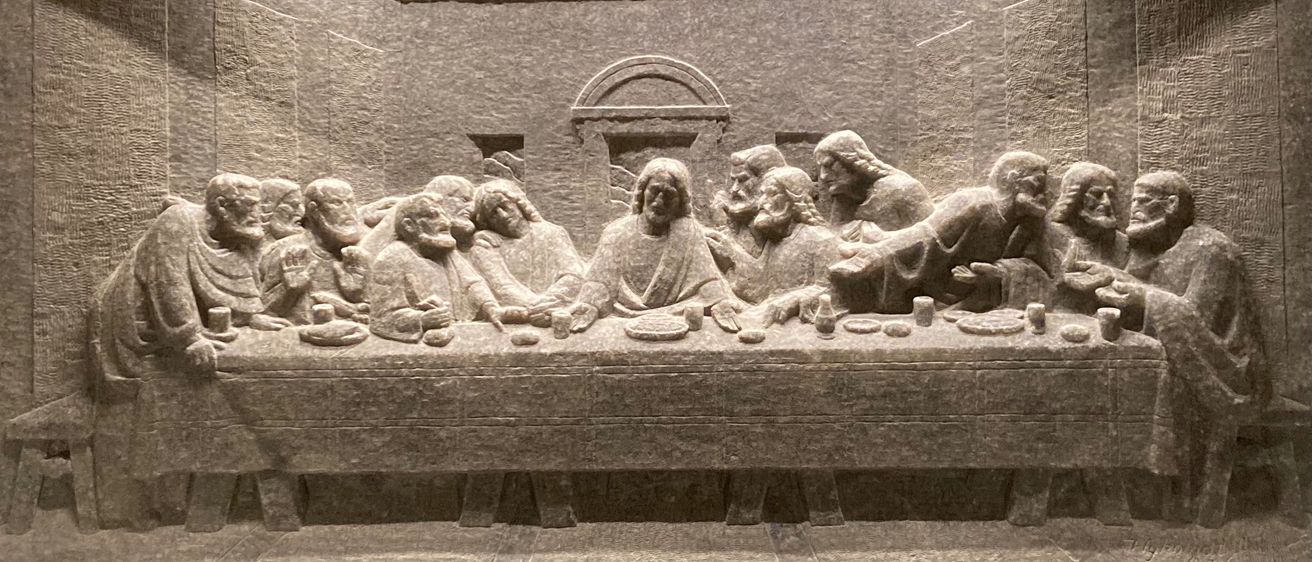 Ein Steinrelief der Szene des Letzten Abendmahls mit Jesus und seinen Jüngern um einen Tisch mit Brot und Wein.