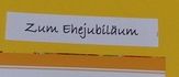 Ein Korb aus Weide mit gelben Samenbeuteln steht auf einem Betonboden. Jeder Beutel zeigt ein Blumenbild und die Phrase 'Lass Liebe Wachsen'.