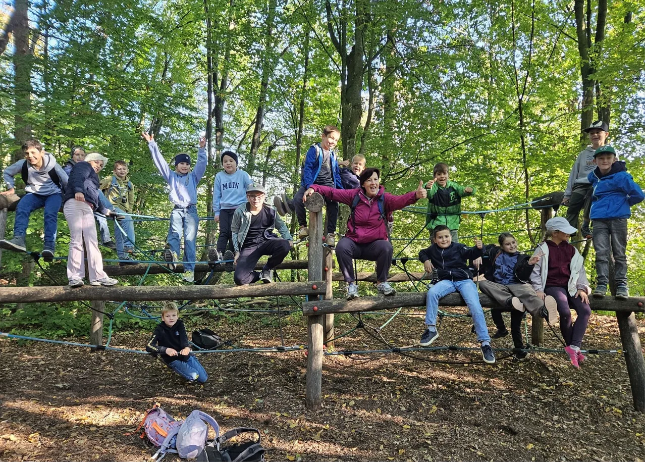 Eine Gruppe von Menschen sitzt auf einer Holzstruktur im Wald.