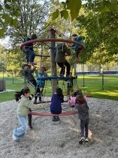 Eine Gruppe von Kindern spielt auf einer großen Kletterstruktur in einem Park.