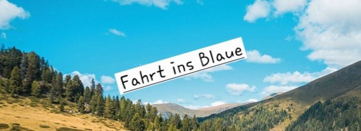 Eine landschaftliche Bergszene mit blauem Himmel und Wolken. Der Text 'Fahrt ins Blaue' ist überlagert und deutet auf eine Reise ins Blaue hin.