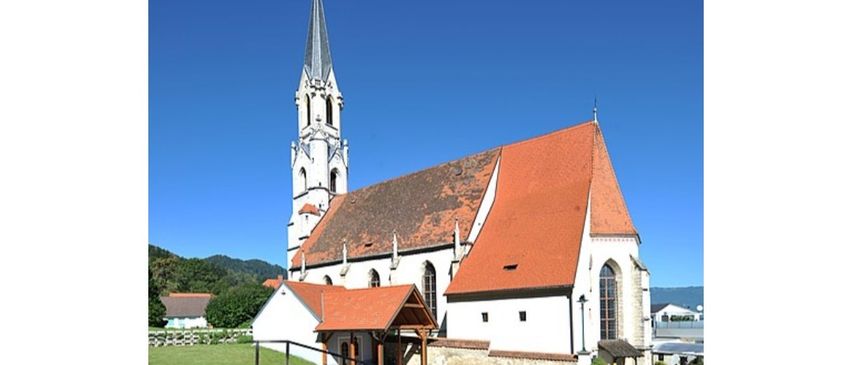 Ein Bild einer Kirche mit einem Turm und einem roten Dach in Maria Buch, Österreich. Die Kirche steht unter Denkmalschutz.