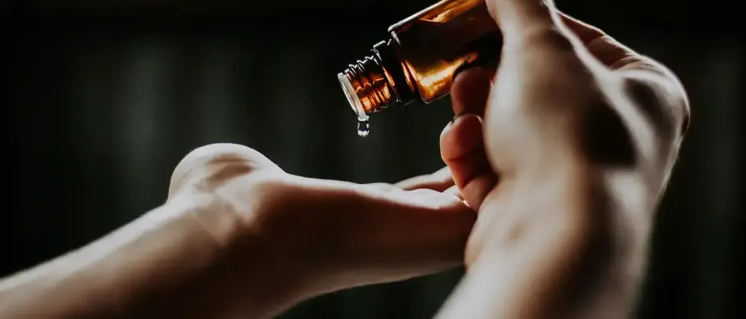 Hände halten eine Flasche mit Pipette, um ätherisches Öl zu extrahieren.