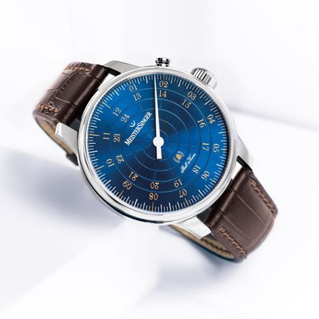 Eine MeisterSinger Uhr mit blauem Zifferblatt und weißen Zeigern, auf einem silberfarbenen Gehäuse und einem braunen Lederarmband. Die Zeit ist 10:10.
