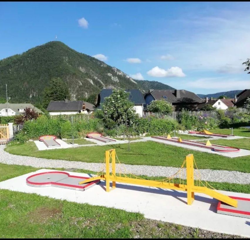 Ein Minigolfplatz mit einer brückenartiger Struktur und einem Berg im Hintergrund.