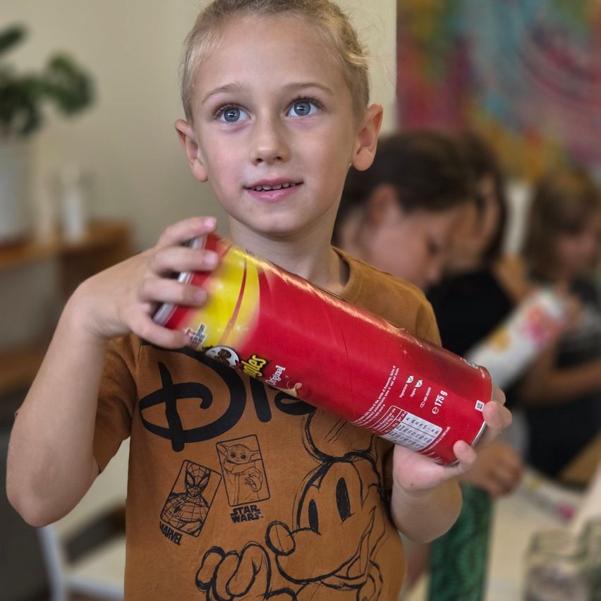 Ein junger Junge in einem braunen Shirt mit Disney- und Marvel-Charakteren hält eine rote und gelbe Tüte Chips.
