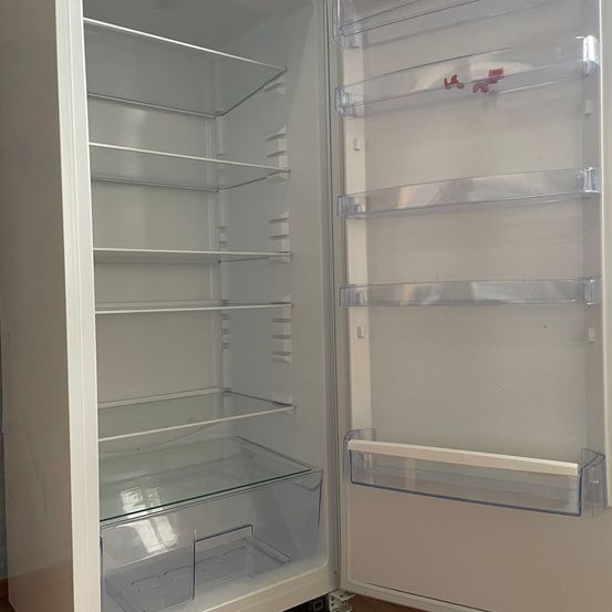 Ein offener weißer Kühlschrank mit transparenten Türen und Regalen. Das Innere ist leer, keine Lebensmittel sind sichtbar.