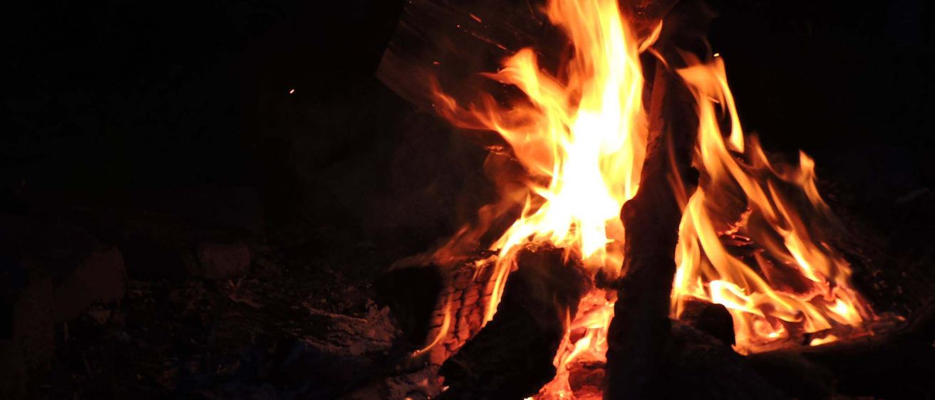 Ein Lagerfeuer brennt hell in der Dunkelheit und wirft einen warmen Schein auf die Umgebung. Die Flammen flackern und tanzen und erzeugen einen faszinierenden Effekt.