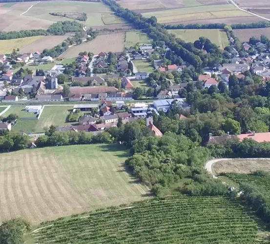 Eine Luftaufnahme einer ländlichen Stadt mit vielen Häusern, Bäumen und einem großen Feld.