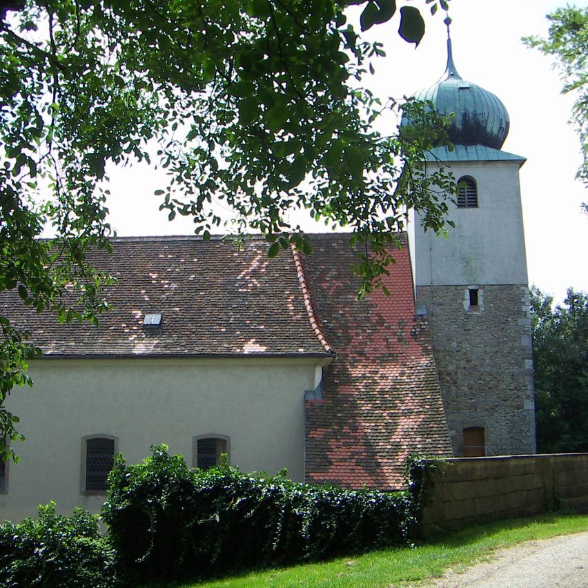 Eine historische Kirche mit einem roten Dach und einem hohen Turm mit einer grünen Kuppel. Der Turm hat ein kleines Fenster an der Seite.