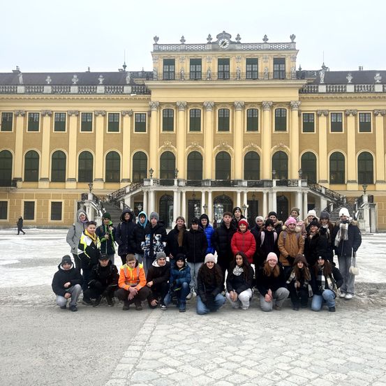 Eine Gruppe von Menschen in Winterkleidung posiert für ein Foto vor dem Schloss Schönbrunn in Wien.
