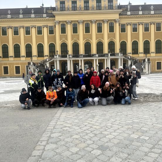 Eine Gruppe von Menschen posiert für ein Foto vor dem großartigen Schloss Schönbrunn in Wien.