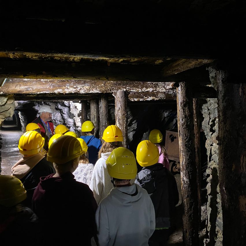 Eine Gruppe von Menschen mit gelben Schutzhelmen geht durch einen Tunnel.