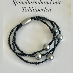 Ein Bild von einem Armband aus schwarzen Kristallen und Tahiti-Perlen mit einer silbernen Schließe, das auf einer weißen Oberfläche präsentiert wird.