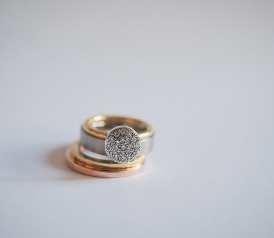 Zwei Ringe, einer mit einem Goldband und der andere mit einem Silberband, sind übereinander gestapelt. Der obere Ring hat ein Diamantmuster.