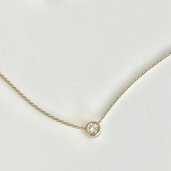 Eine goldene Kettenkette mit einem kleinen Diamantanhänger auf weißem Hintergrund.