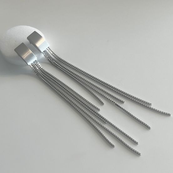Ein Paar silberne Kettenohrringe mit schlankem, modernem Design. Die Ohrringe haben mehrere fließende Stränge.