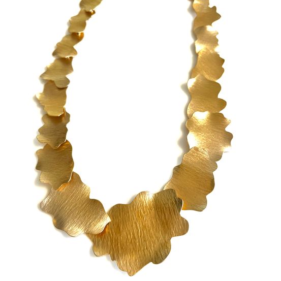 Eine goldplattierte Halskette mit Muschelschalen-Rändern, präsentiert vor einem weißen Hintergrund.