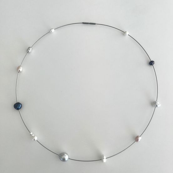Eine silberfarbene Halskette mit verschiedenen Perlen, einschließlich blau, weiß und pink, gleichmäßig verteilt.