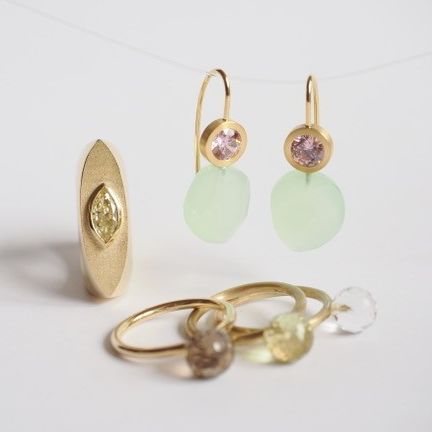 Eine Sammlung von vergoldetem Schmuck, einschließlich Ohrringe mit grünen und rosa Steinen, einem Ring mit gelbem Stein und einer Gruppe von Ringen mit verschiedenfarbigen Steinen.