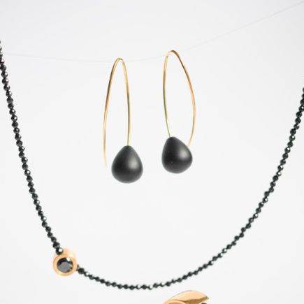 Eine goldene und schwarze Perlenkette mit Ohrringen und zwei Ringen, einer mit einem schwarzen Stein.