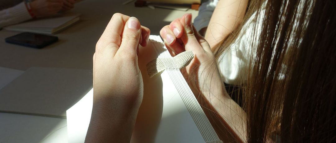 Mehrere Personen sitzen um einen Tisch herum, eine demonstriert eine Technik mit einem Stück Stoff.