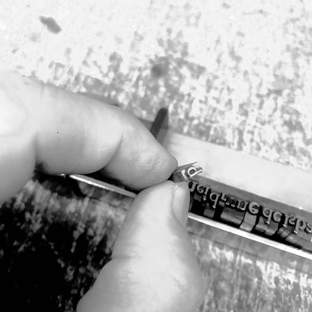Eine Hand hält einen Buchstaben 'O' auf einer Schreibmaschinentastatur fest, was auf ein Close-up eines manuellen Tippprozesses hinweist.