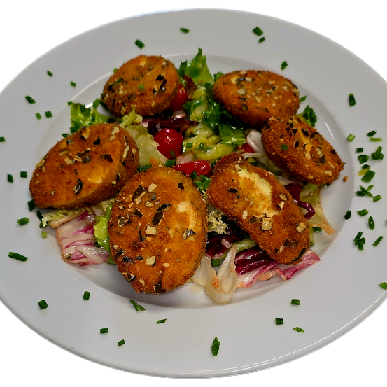 Ein weißer Teller mit einem Salat, der mit gebratenen Kugeln bestreut ist und schwarze Samen hat. Der Salat hat grüne Blätter, rote Tomaten und rote Zwiebeln.